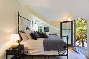 Bedroom with wood-type flooring, access to exterior, and vaulted ceiling