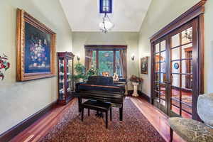 Living area with french doors, wood-type flooring, and vaulted ceiling