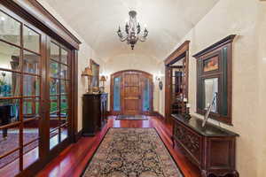 Entryway with lofted ceiling, french doors, dark hardwood / wood-style floors, and an inviting chandelier