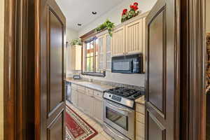 Kitchen with light tile patterned flooring, appliances with stainless steel finishes, light stone countertops, and sink