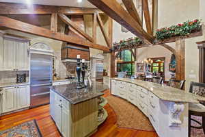 Kitchen featuring built in refrigerator, a kitchen breakfast bar, a center island, white cabinets, and light wood-type flooring