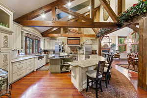 Kitchen featuring a center island, light wood-type flooring, a kitchen breakfast bar, a notable chandelier, and light stone countertops