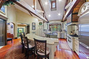 Kitchen with hardwood / wood-style flooring, stainless steel appliances, a center island, and light stone counters