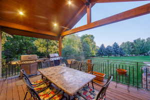 Deck at dusk with area for grilling and a yard