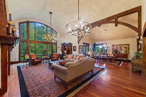 Living room featuring wood-type flooring, high vaulted ceiling, and a chandelier