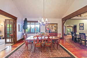 Dining space with wood-type flooring, lofted ceiling, and a chandelier