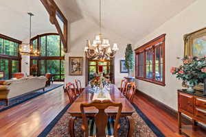 Dining area featuring lofted ceiling, dark wood-type flooring, and an inviting chandelier