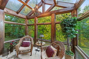 Sunroom featuring vaulted ceiling, a wealth of natural light, and an inviting chandelier