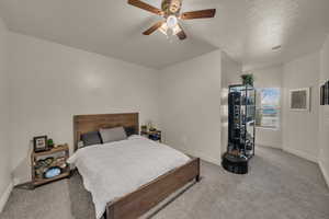 Carpeted bedroom featuring a textured ceiling and ceiling fan