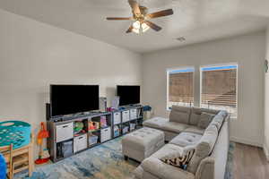 Living room featuring ceiling fan, a textured ceiling, and hardwood / wood-style floors