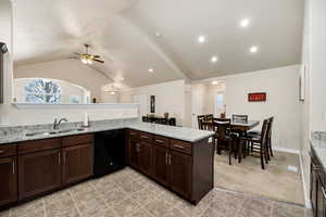 Kitchen with dishwasher, sink, kitchen peninsula, light stone countertops, and light carpet