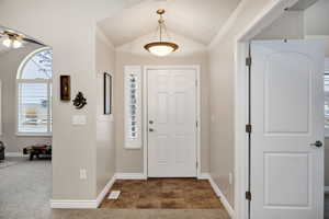 Entryway with dark tile patterned flooring, vaulted ceiling, and ceiling fan