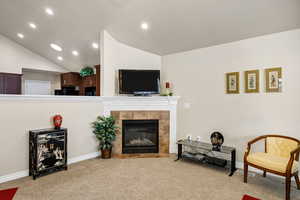 Carpeted living room with lofted ceiling and a tile fireplace