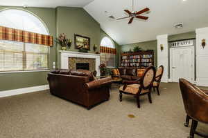 Clubhouse Carpeted living room with ceiling fan, high vaulted ceiling, and a fireplace