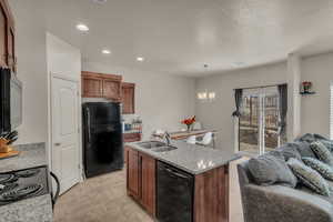 Kitchen featuring decorative light fixtures, a chandelier, black appliances, light stone counters, and sink