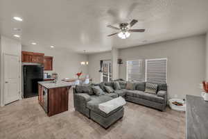 Living room featuring a textured ceiling, ceiling fan with notable chandelier, and sink