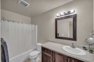 Full bathroom featuring a textured ceiling, toilet, vanity, and shower / bathtub combination with curtain