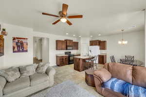 Living room with ceiling fan with notable chandelier and sink