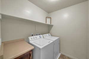 Laundry room with washer and clothes dryer and a textured ceiling