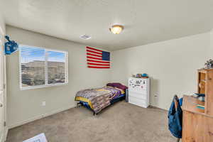 Bedroom with light colored carpet and a textured ceiling