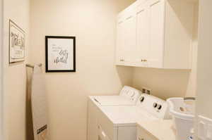 Clothes washing area featuring cabinets and independent washer and dryer