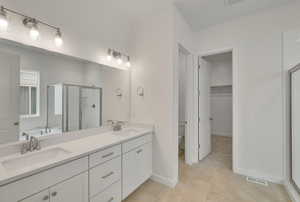 Bathroom with walk in shower, tile patterned floors, toilet, and vanity