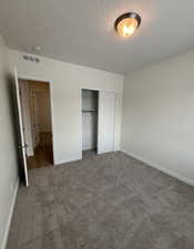 Unfurnished bedroom featuring a closet, carpet, and a textured ceiling