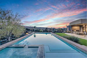 Pool at dusk with an in ground hot tub and a patio