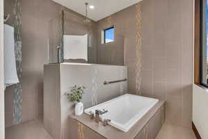 Bathroom with tile walls, tile patterned flooring, and independent shower and bath