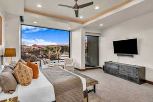 Carpeted bedroom with a raised ceiling and ceiling fan