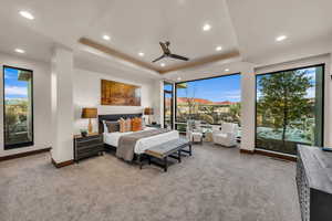 Bedroom featuring light carpet, a raised ceiling, and ceiling fan