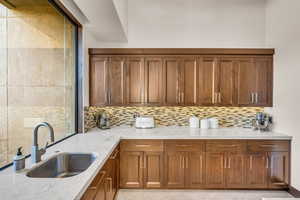 Kitchen featuring light stone counters, sink, and tasteful backsplash