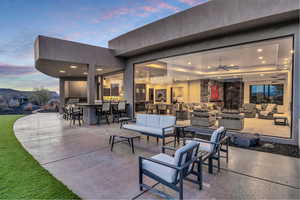 Patio terrace at dusk with an outdoor living space, an outdoor bar, and ceiling fan