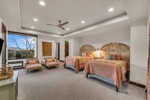 Carpeted bedroom with ceiling fan and a tray ceiling