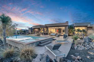 Pool at dusk featuring an in ground hot tub and a patio