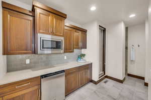 Kitchen with stainless steel microwave, dishwasher, and backsplash