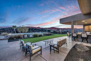 Patio terrace at dusk featuring a mountain view, an outdoor bar, and a lawn