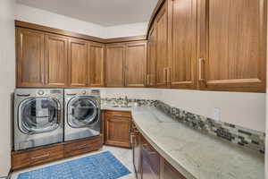 Clothes washing area with independent washer and dryer, cabinets, and sink