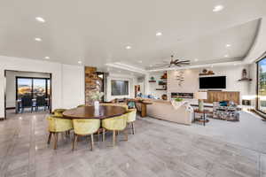 Dining area with ceiling fan, a fireplace, and a tray ceiling