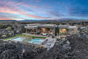 Pool at dusk with an in ground hot tub, a mountain view, and a patio area