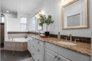 Bathroom with vanity and tiled bath