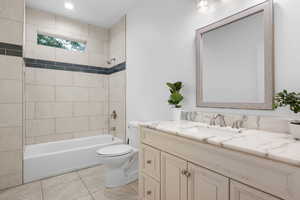 Full bathroom featuring tile patterned floors, toilet, tiled shower / bath combo, and vanity