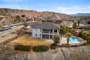 Rear view of property featuring a fenced in pool, a mountain view, a patio, and a balcony