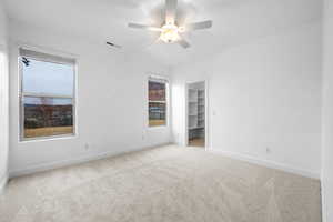 Unfurnished bedroom featuring a spacious closet, light colored carpet, ceiling fan, and a closet