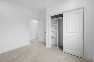 Unfurnished bedroom featuring light colored carpet and a closet