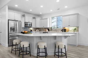 Kitchen with a breakfast bar, appliances with stainless steel finishes, a center island, and white cabinets