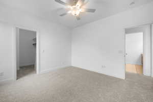 Unfurnished bedroom with light carpet, a spacious closet, a closet, and ceiling fan