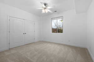 Unfurnished bedroom with light carpet, a closet, and ceiling fan