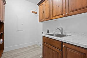 Washroom with sink, electric panel, cabinets, washer hookup, and hookup for an electric dryer