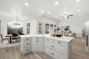 Kitchen featuring light stone countertops, white cabinets, light hardwood / wood-style floors, and decorative light fixtures